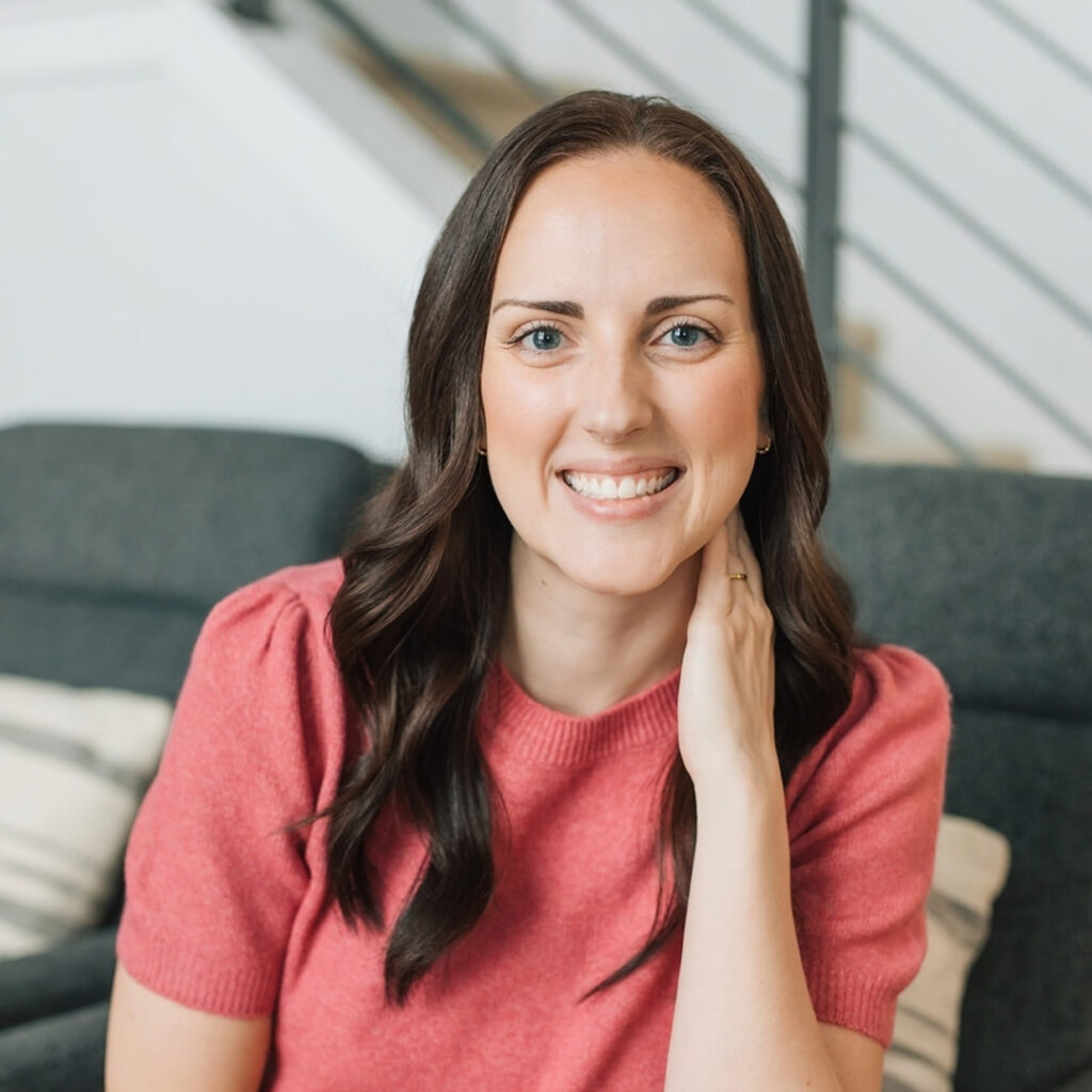 Photo of the business owner sitting on a chair smiling with hand on neck.